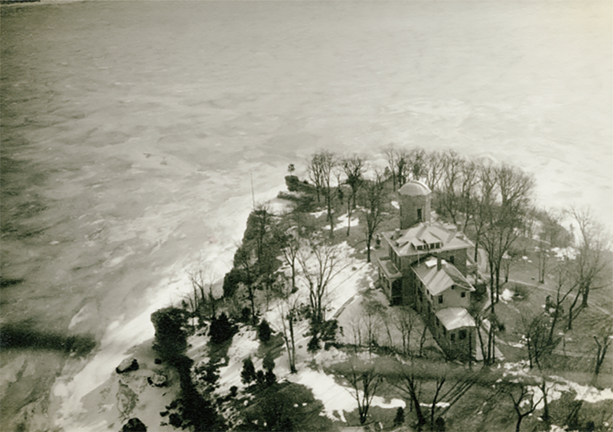A sky view of the back of Cook Castle on Gibraltar Island shows the building's rounded tower, the island's cliffs and a lot of Lake Erie