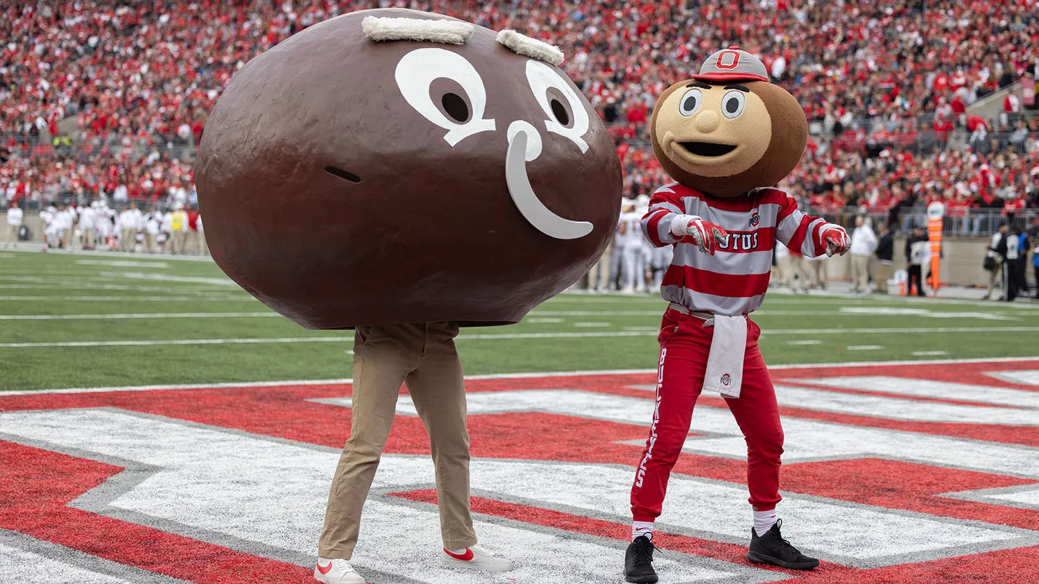 In a crowded Ohio Stadium, the modern Brutus dances along side a vintage one. The VIntage one is a giant papier mache head painted brown. His cardboard smile is falling off.