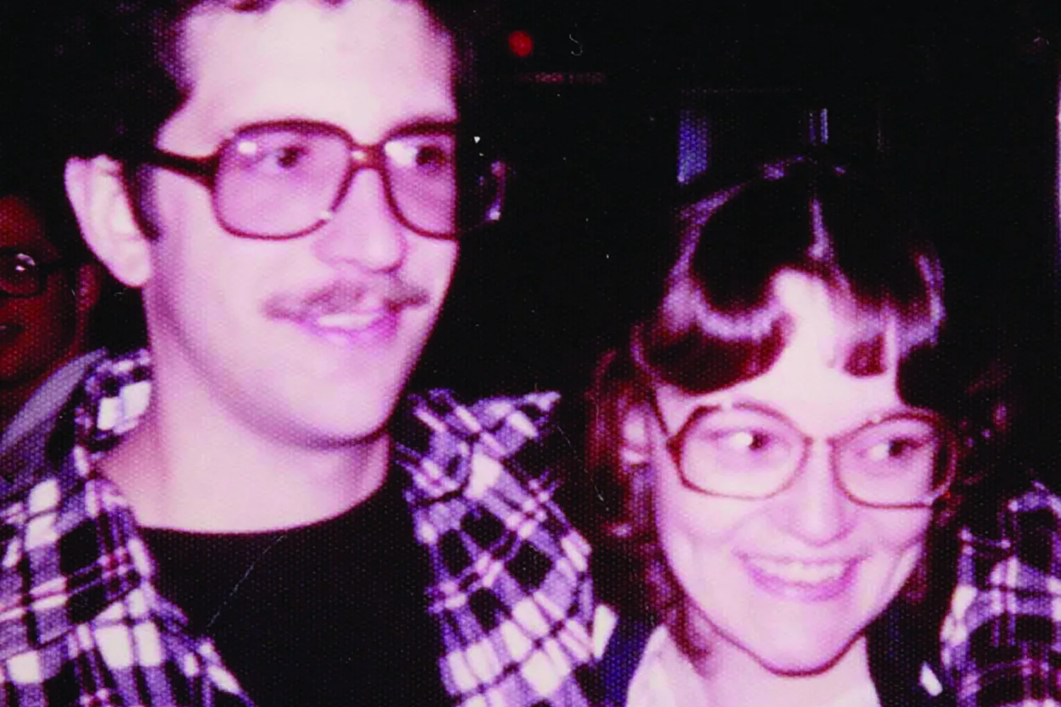 Another 1970s photo shows the same couple. He has his arm around her shoulders and they both wear the big glasses popular in that era.