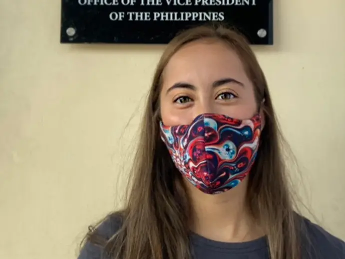 Woman wearing cloth mask with multi-colored patten and gray t-shirt