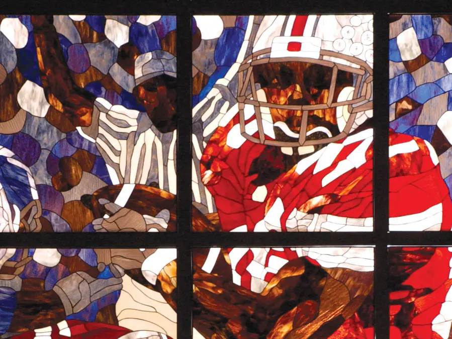 A portion of a stained glass window shows a Buckeye player rushing with the football