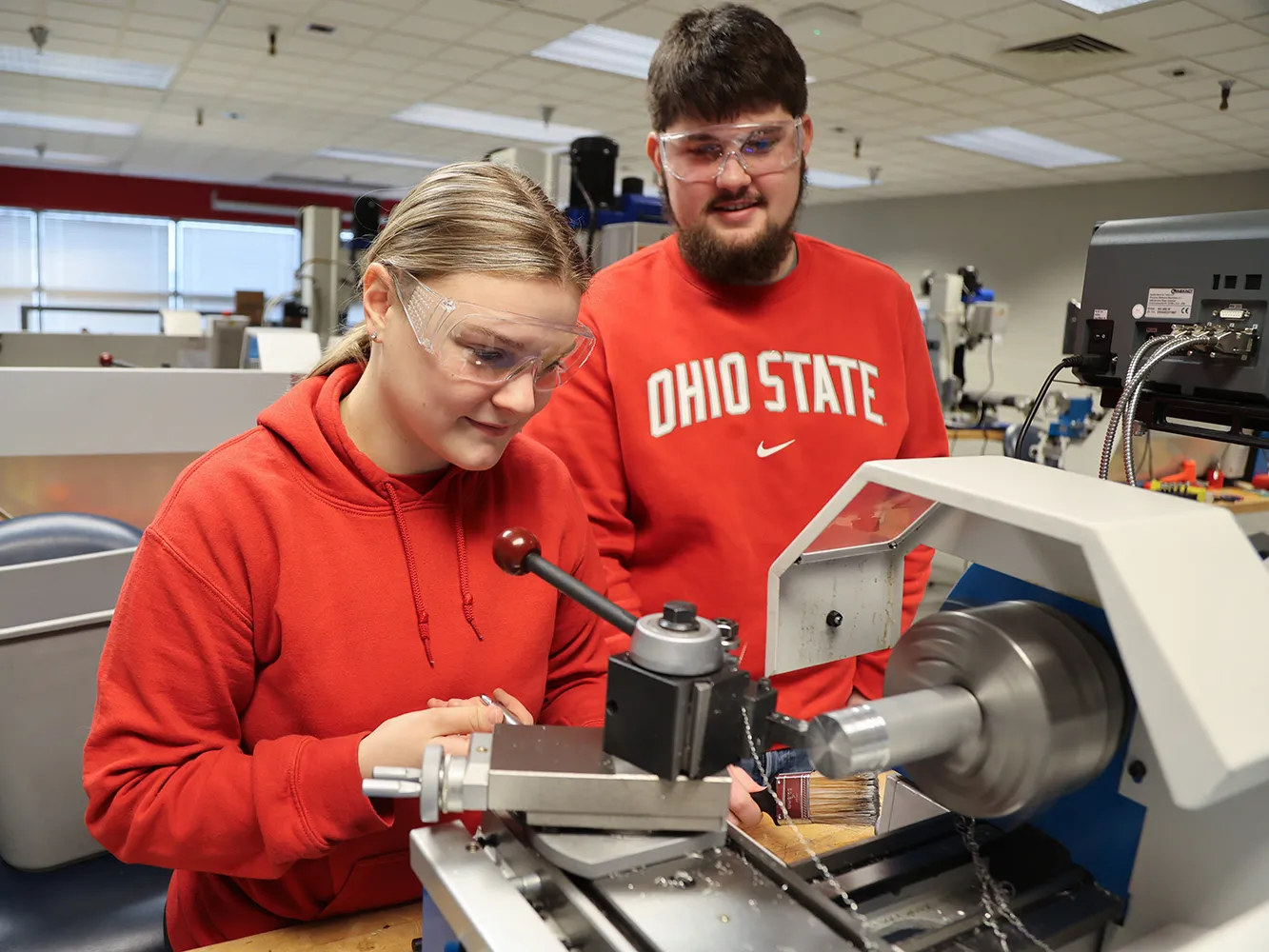 Two Ohio State students work in a manufacturing classroom. A lave is in front of them. Both are white; one is a young blonde woman and the other is a man with dark hair and beard.