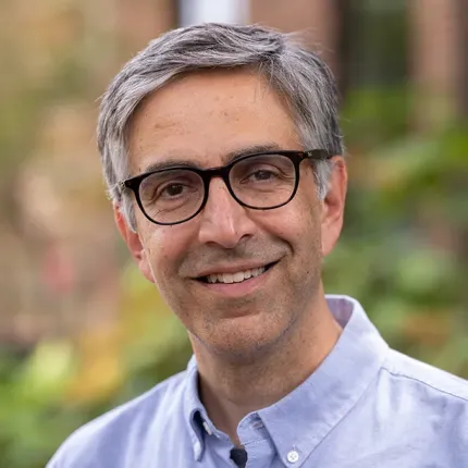 A smiling man with glasses poses for a photo. He has graying hair and an expression that says he's a good listener.
