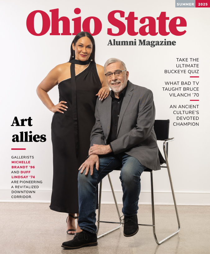 The summer 2025 cover of Ohio State Alumni Magazine shows an older man sitting in a chair and a woman standing next to him, resting her arm on his shoulder. They seem comfortable with each other and elegant; both are dressed up. The woman has a knowing smile, a long black dress and scarf, and straight hair parted in the middle. She is Latina. The man wears a suit coat, jeans and a black button-down. He is white and has gray hair and beard and glasses.