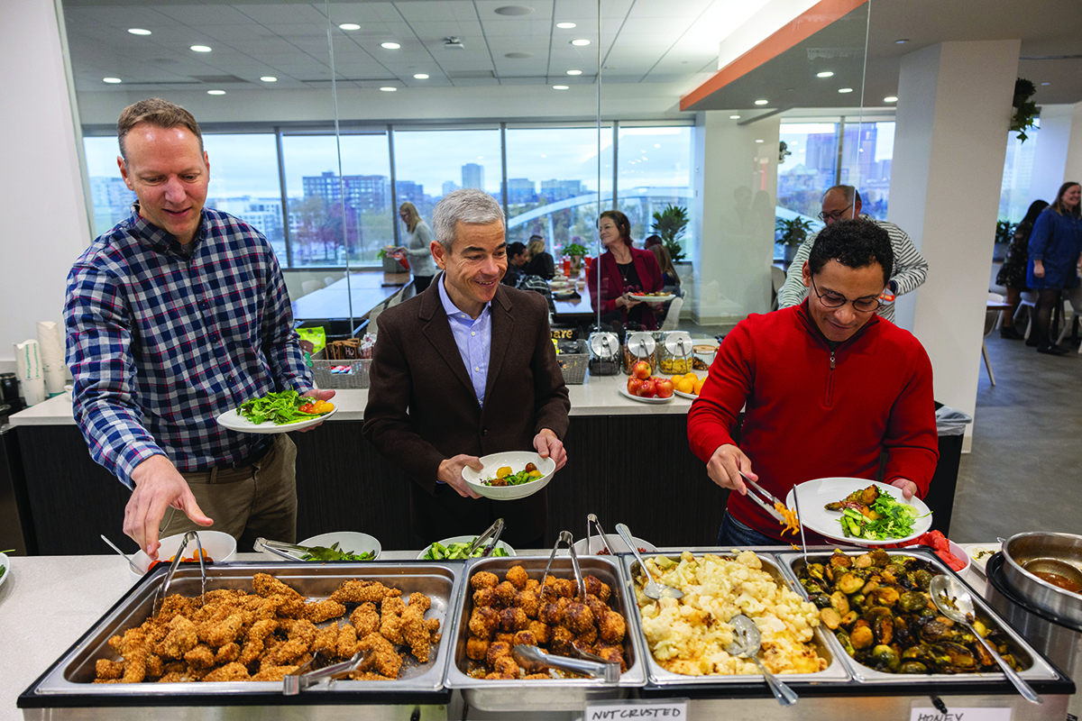 Matt Scantland and employees of his company, AndHealth, help themselves to food at a buffet in their office cafeteria. 