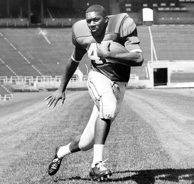 A young Ben Espy tucks the football into his elbow as he runs sideways. His expression shows his determination.
