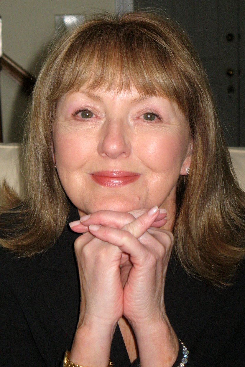 Carole Gerber rests her chin on her clasped hands and softly smiles in this portrait of her.
