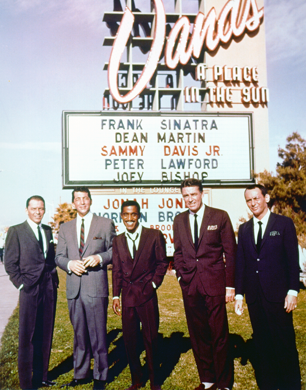 Looking debonair in 1960s suits and skinny ties, Frank Sinatra, Dean Martin, Sammy Davis Jr., Peter Lawford and Joey Bishop pose for a photo in front of a Las Vegas sign bearing their names in that order. 