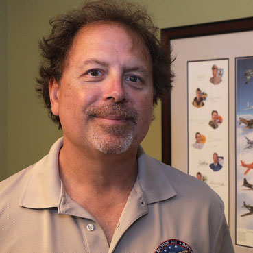 Richard Hughes smiles in a snapshot portrait. He's a white man with brown eyes and brown hair, and he looks happy and competent.