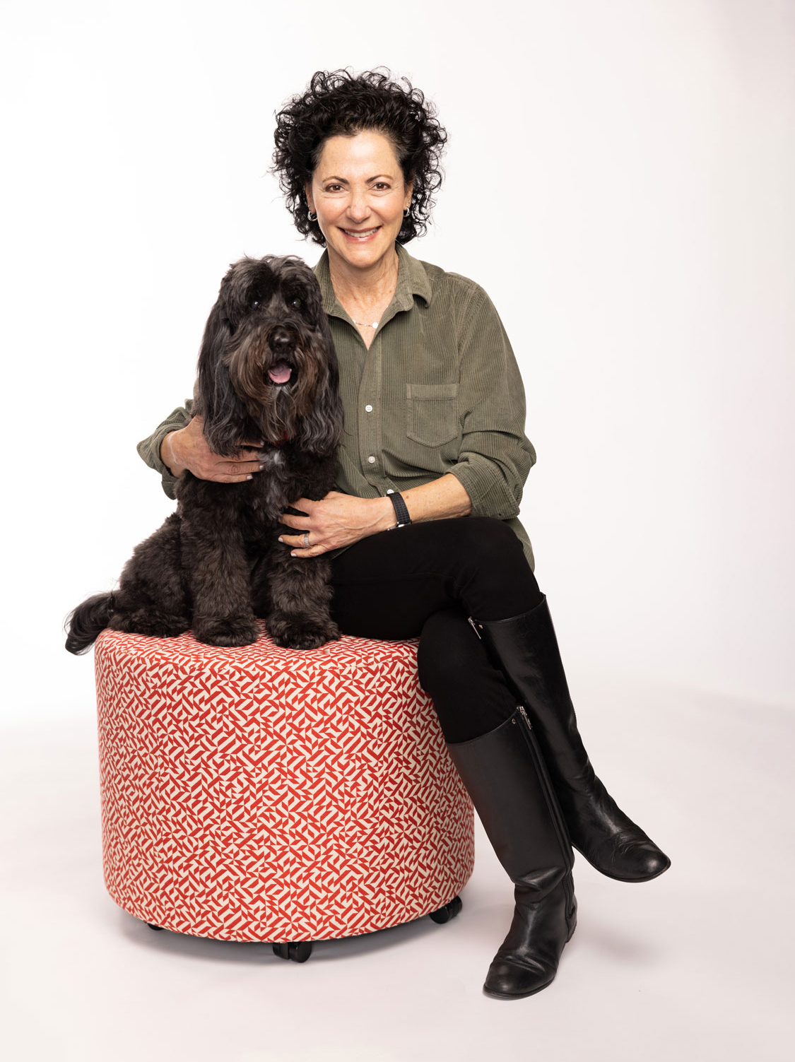 Linda Kass smiles as she poses with her dog, a black poodle-and-labrador mix.