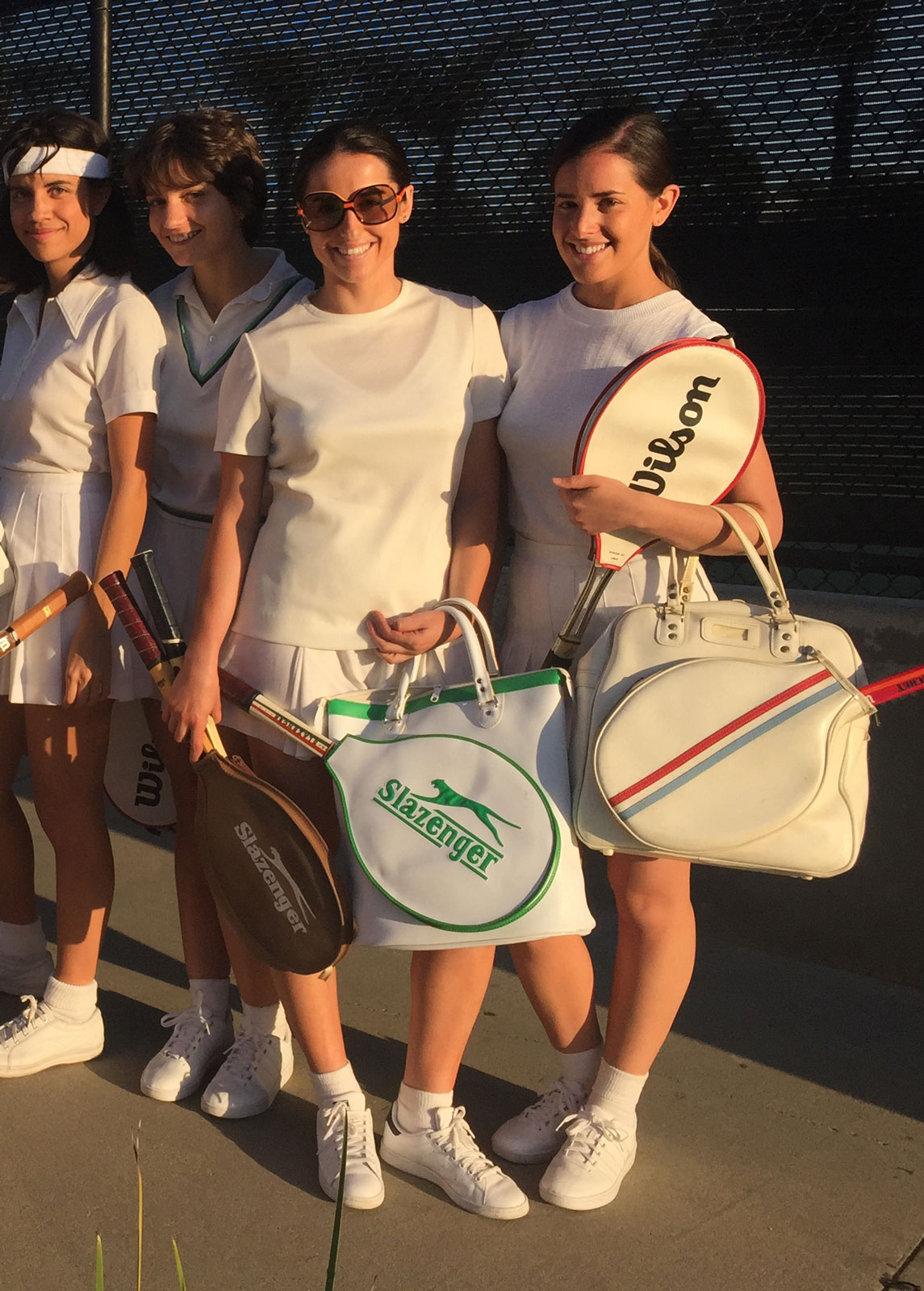 Tennis players pose for a photo standing in a tight group. 