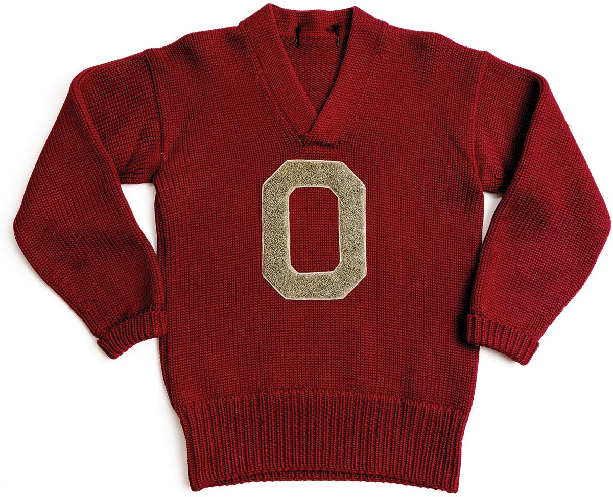 A scarlet sweater with a gray Block 0 is laid out as if the wearer is standing with hands on hips.