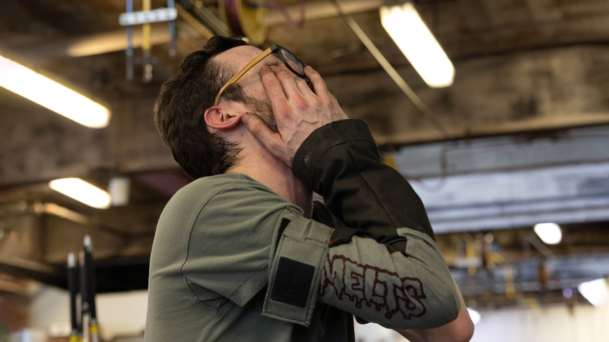 A man who seems tired or frustrated rubs his eyes while tipping his face toward the ceiling. 