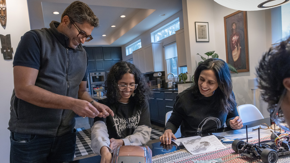 Bhakti’s family—husband, college age daughter and teen son, whose hair appears at the edge of the photo—works on a model car at the dining room table in their home.