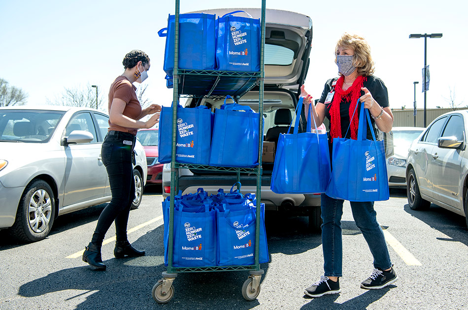 Two women distribute bagged delivery of supplies 