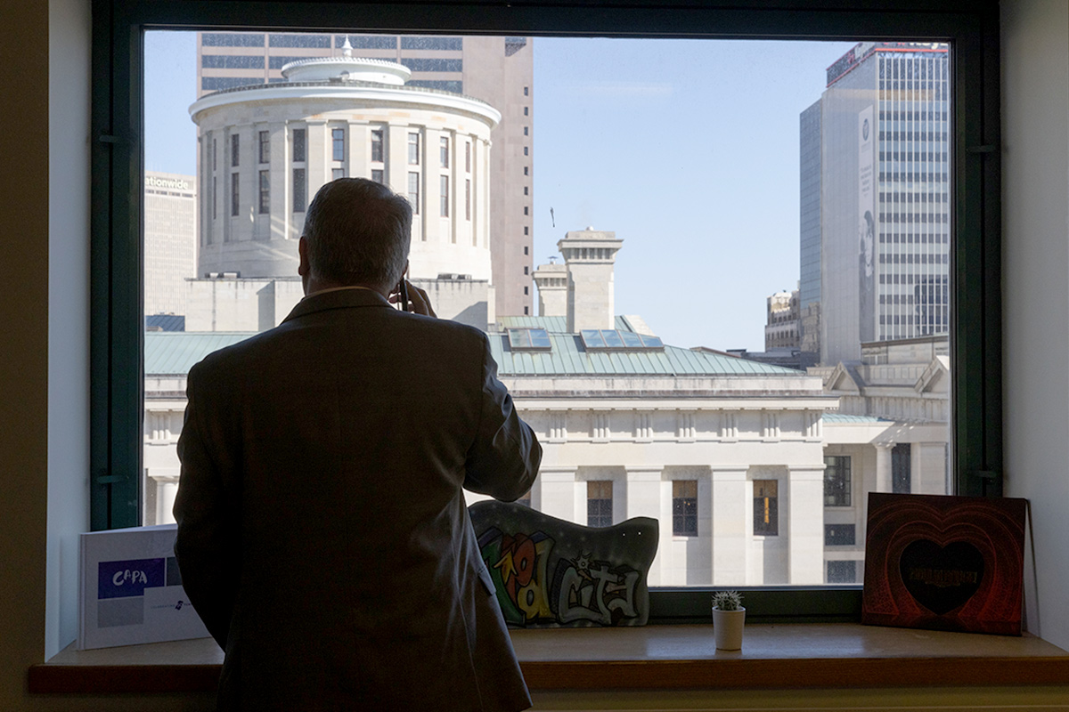 Whittington takes a phone call while viewing out his window the Ohio Capital building