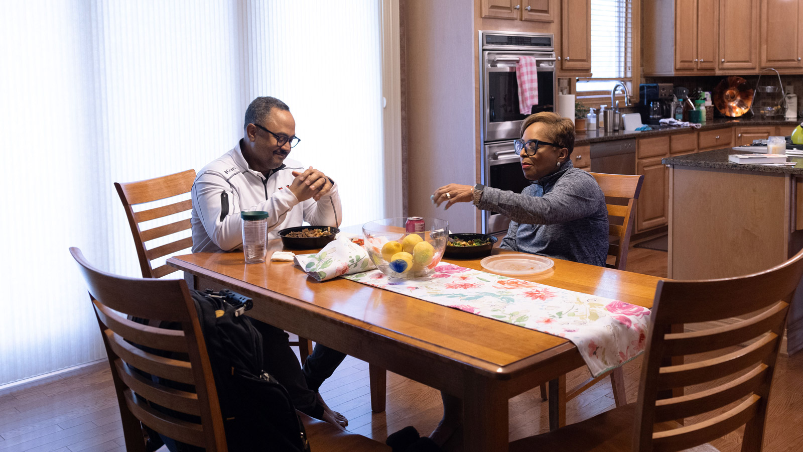 Tracy Turner and her husband, Murvin, eat prepared food (salads or grain bowls-it's hard to tell) at a table next to their kitchen