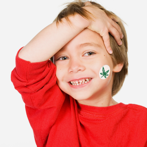 A small boy proudly shows a Buckeye leaf decal applied to his cheek
