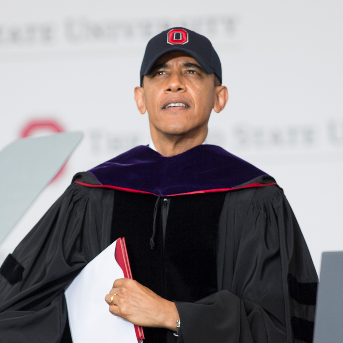 Former President Obama wears a block O baseball cap and grad robes.