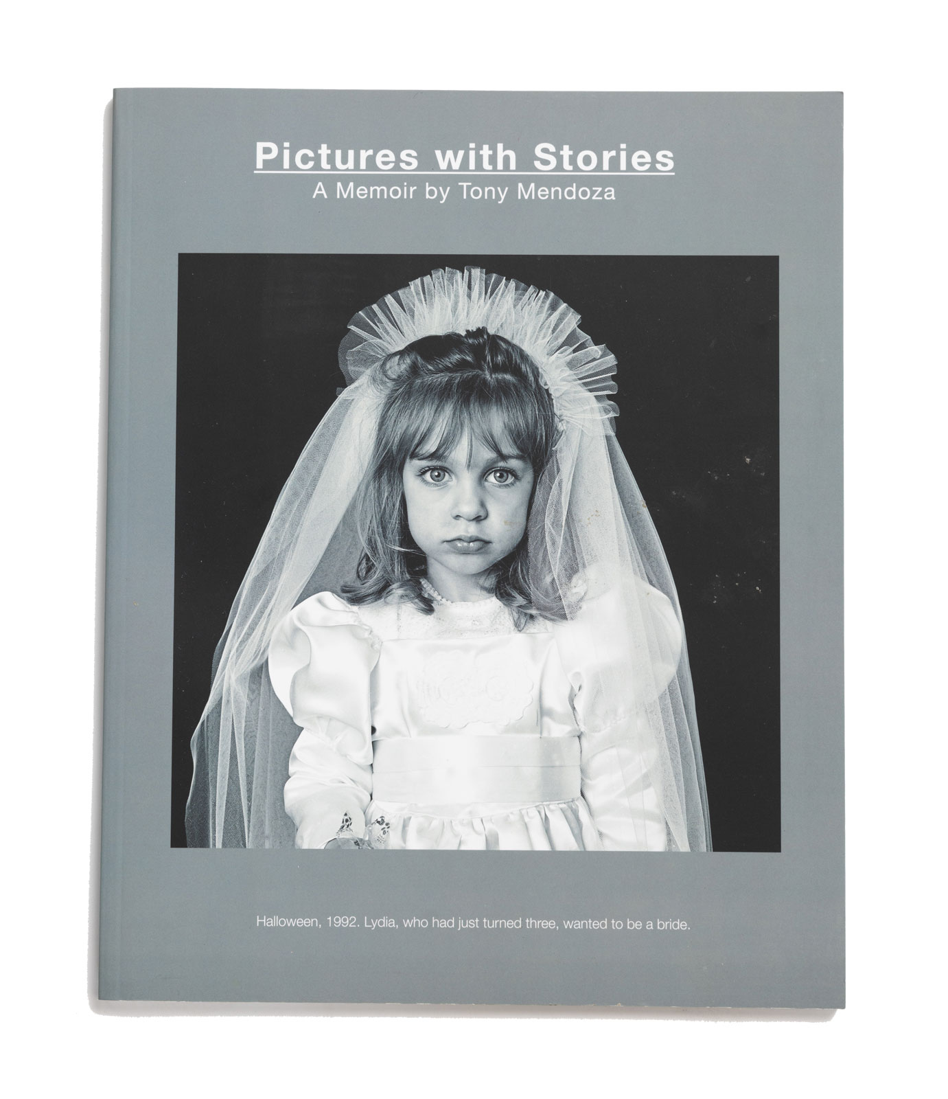 The cover of the book "Pictures with Stories" shows a girl wearing a first communion dress and veil and staring just off of the photographer