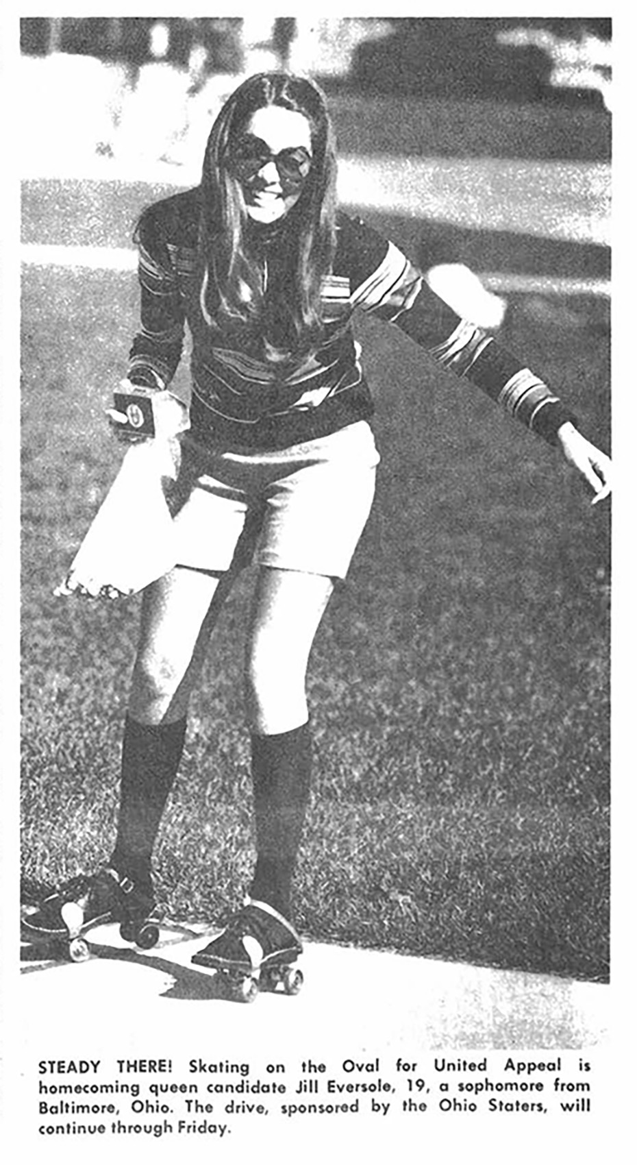 A black and white photo from a newspaper shows a female college students wearing sunglasses and rollerskates. She has on a striped shirt, knee-high socks and a big smile.