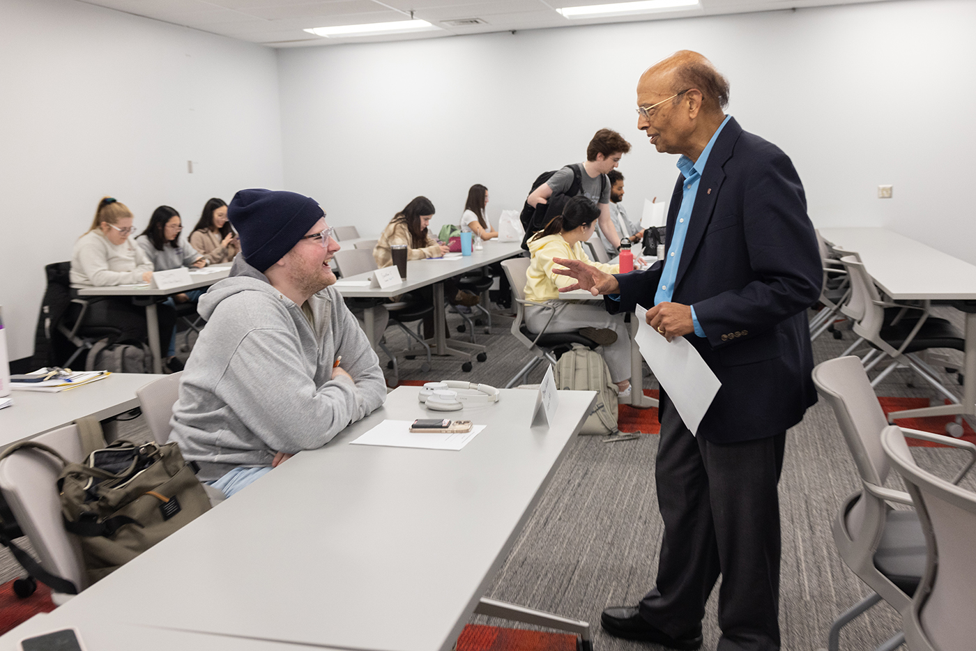 In a classroom, Milap Nahata talks with a student, who's laughing in response.