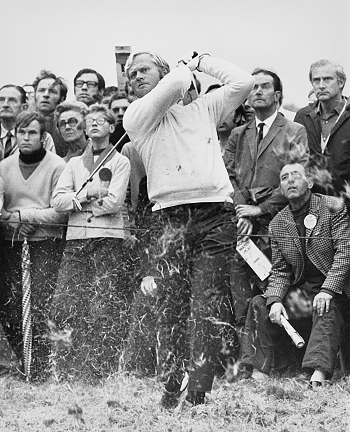 jack nicklaus watche sthe ball go after taking a swing. A crowd behind him all look in the same direction.