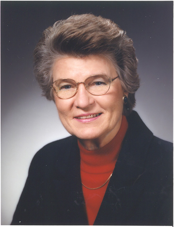 Teater is shown as an older woman in this formal headshot. She has a friendly smile and her her is reminiscent of the poofed-up style she wore as a younger woman, though it's very tasteful.