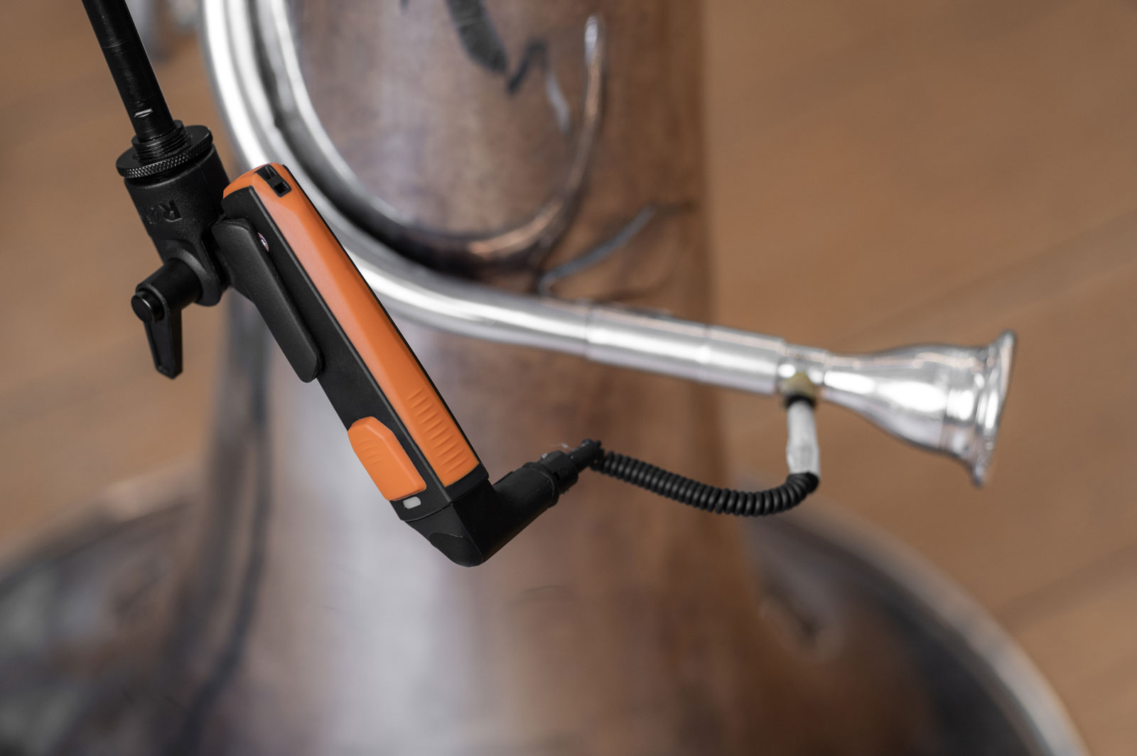 A close-up view of a small plastic anemometer and plastic tubing screwed into the side of a tuba’s mouthpiece