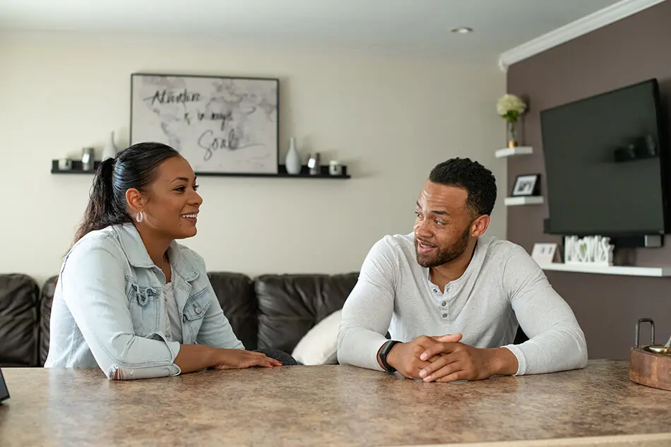 woman and man sit at desk in house talking