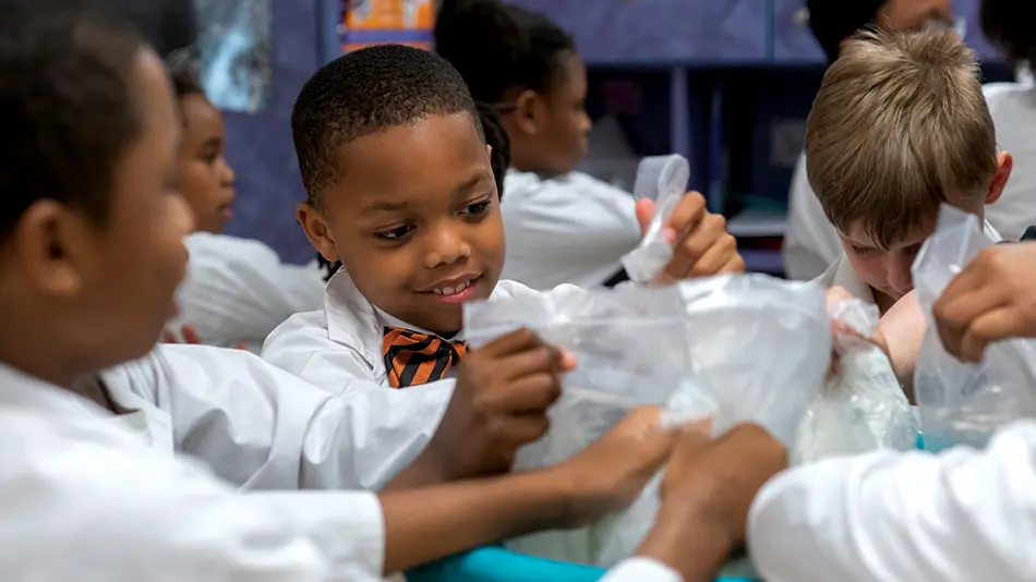 A group of young children are holding plastic bags as part of a hands-on science experiment