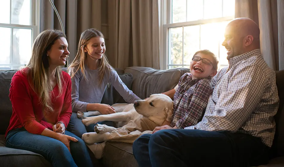 Family smiling and petting a dog while sitting on a couch
