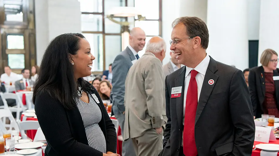 A man and woman in business dress chat at an event at the Ohio Statehouse