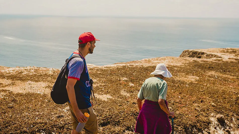 Brad and Grandma Joy are hiking along a dirt path along a coastline.