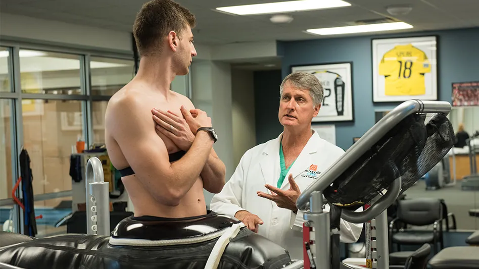 Edwards is standing next to a young man on a treadmill.