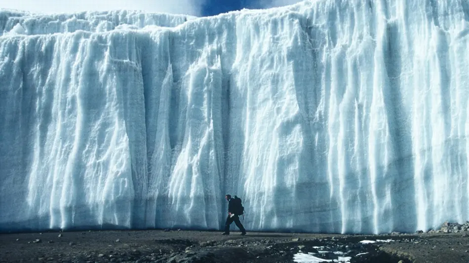 man walks in front of glacier