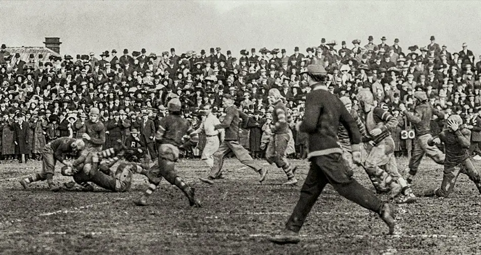 Black and white archival photo of a football game being played in 1909. 