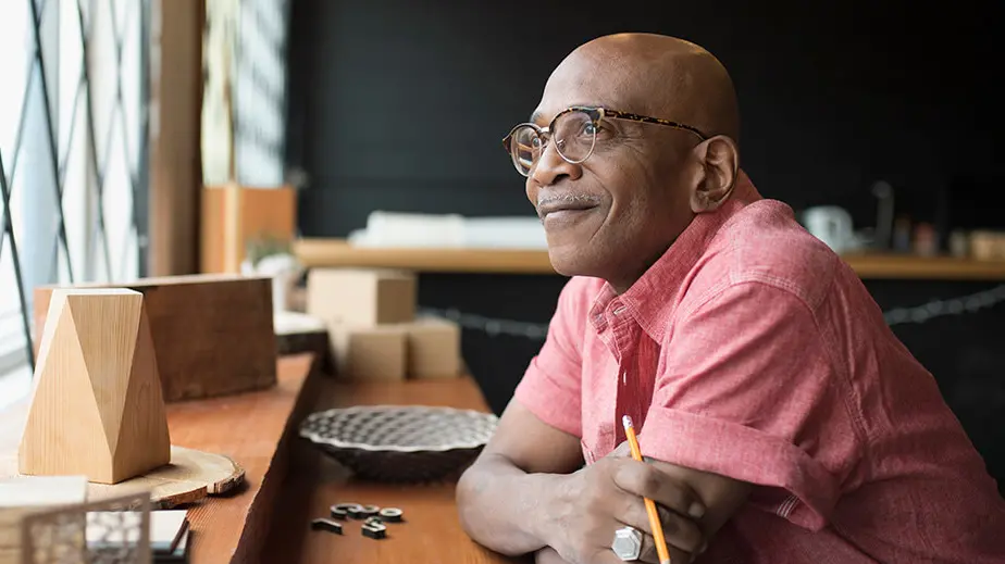 Image of bald Black man with mustache and looking out a window