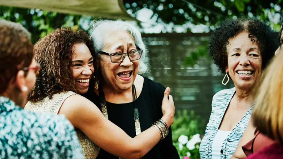 A young woman is hugging an older woman while standing with a group.