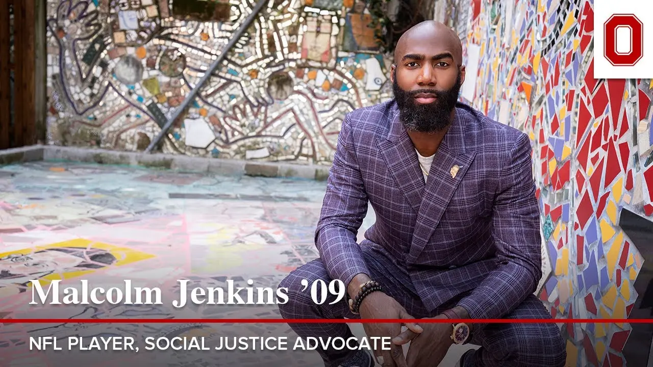 Malcom Jenkins, a bald Black man, wears a blue checked suit