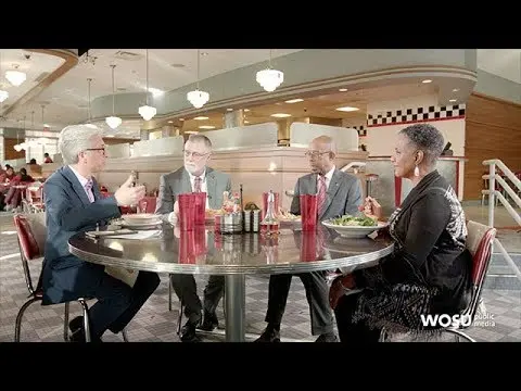 4 people are sitting around a diner table in discussion.