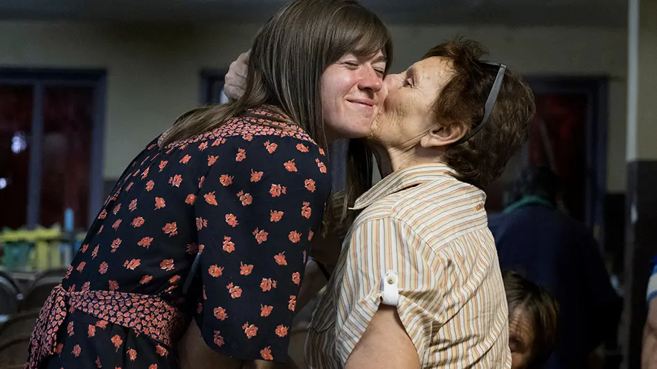 old lady kisses the cheek of a younger woman