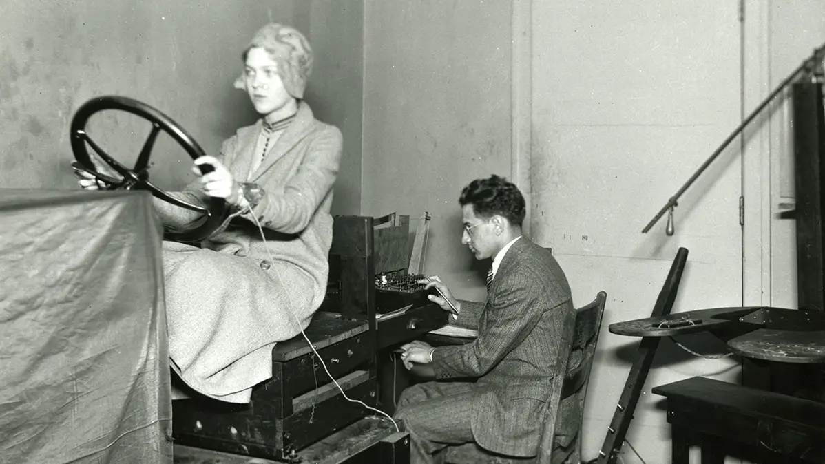 Woman performs driving simulation while professor watches