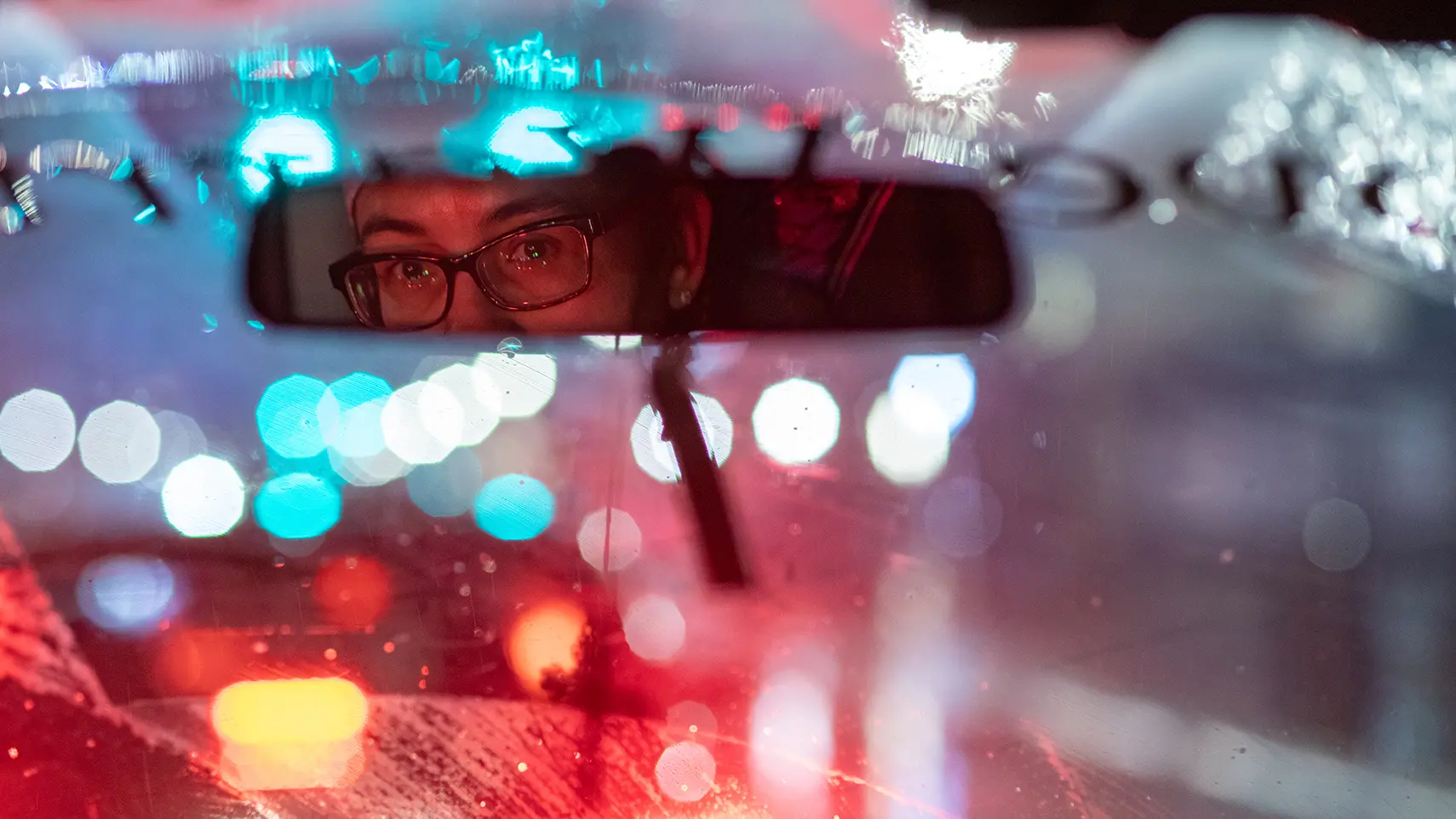 Esther Flores looking in her rear view mirror at night while driving