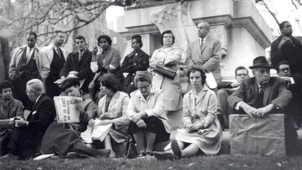black and white photo of a group of people sitting and looking on