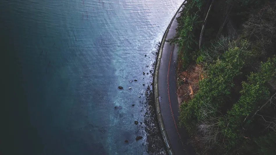 rocky beach where the water meets a highway and forest in Canada