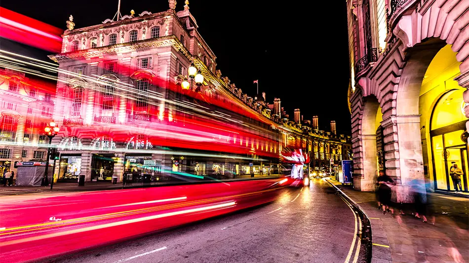 long exposure showing the streaming lights of a bus in Picadilly Square London