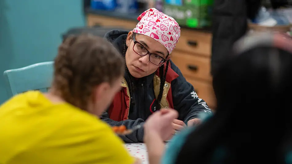 Esther Flores wearing a bandana listening to a woman speak