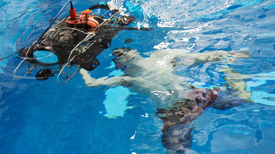 male student goes underwater to check a submersible robot 