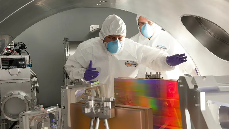 two researchers in hazmat gear inspecting a machine in the Laser Fusion Laboratory